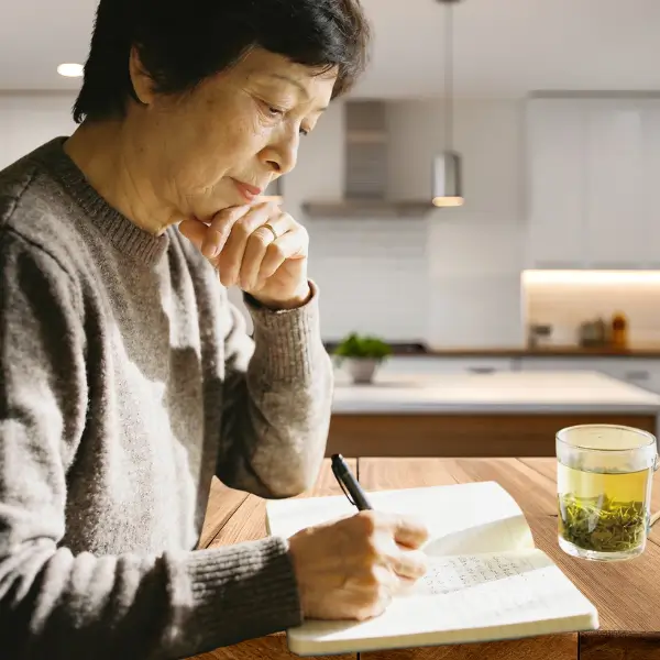 Femme sereine écrivant dans un journal pour son épanouissement personnel et son bien-être mental