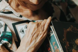 Femme senior consultant un album de photographies familiales pour commencer sa généalogie